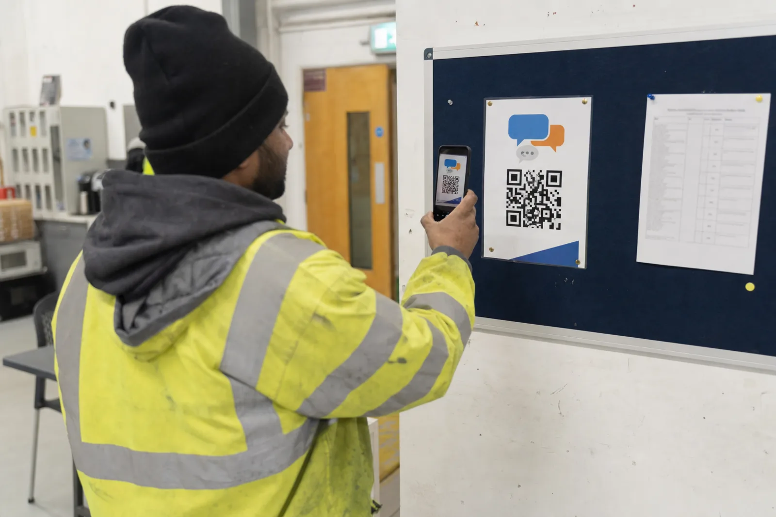Frontline employee scanning a feedback poster in a staff area
